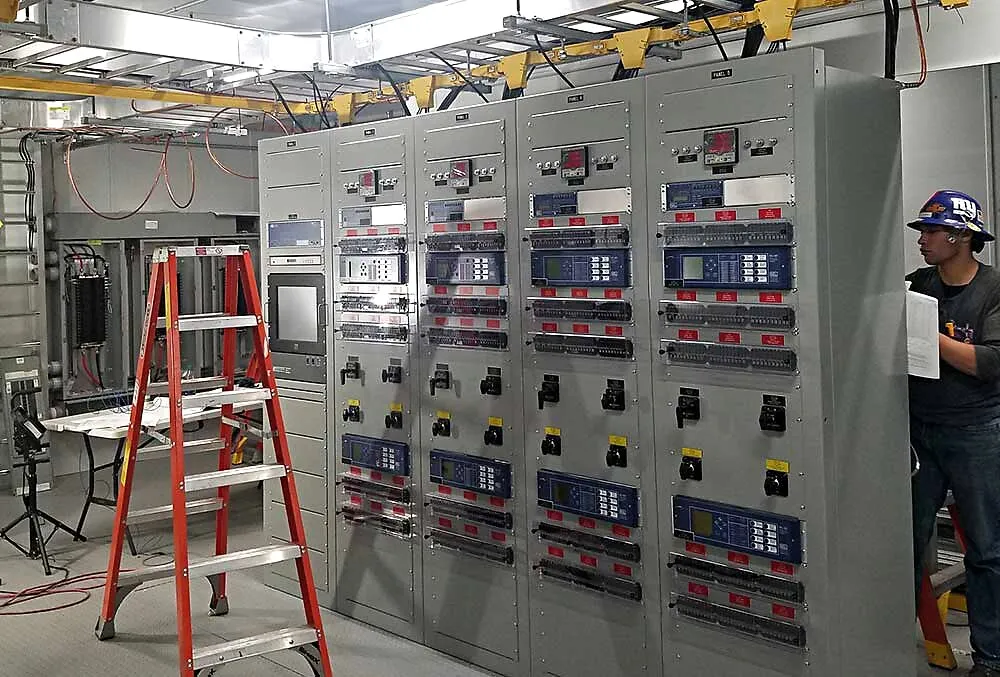 KLM electrician working in a bank of industrial metering and control panels